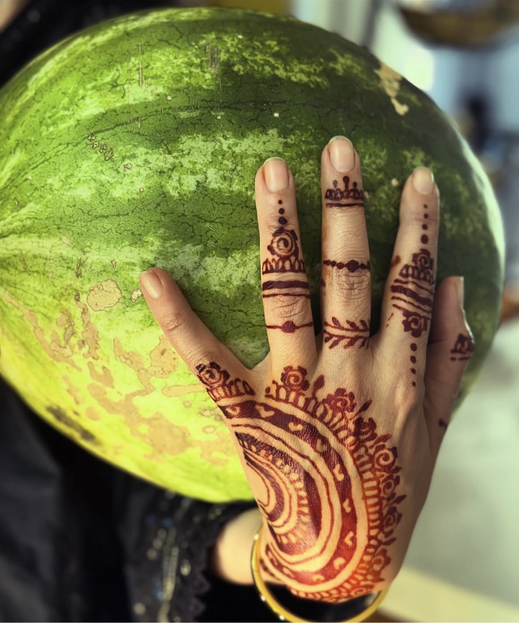 Sabina Khan-Ibarra’s henna-painted hand resting on a watermelon